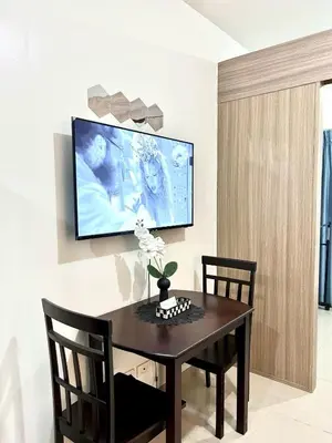 a dining room with a table and a tv on a wall at Stylish 1BR Condo at Shore Netflix & Chill-Pool View in Manila
