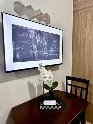 a television on a wall with a table with a vase of flowers at Stylish 1BR Condo at Shore Netflix & Chill-Pool View in Manila