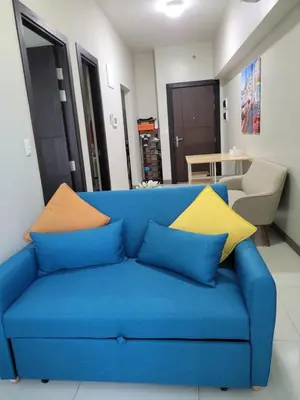 a blue couch with colorful pillows in a living room at BGC Uptown Park Suites Tower 1 - 2 Bedroom and 2 Bath Condo in Manila