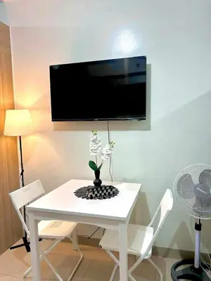 a white table with a vase of flowers on it at 1 Bedroom Condo at Shore 2 Near Airport with Balcony & Pool View in Manila