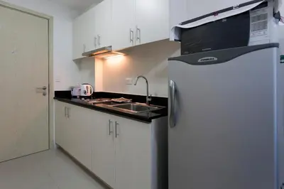 a kitchen with a sink and a refrigerator at Cozy 1BR Condo at Jazz Residences in Manila