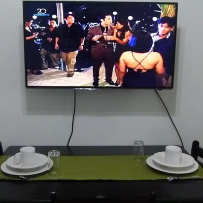 a table with two white hats and a tv on a wall at Cozy 1BR Condo at Jazz Residences in Manila