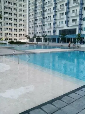 a large swimming pool in front of a large building at Fully Furnished 1BR Condo at Jazz Residences in Manila