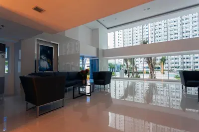 a lobby with chairs and tables and large windows at Fully Furnished 1BR Condo at Jazz Residences in Manila