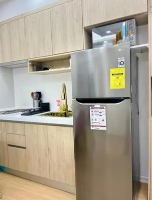 a stainless steel refrigerator in a kitchen with wooden cabinets at Chic BGC Stay - Hotel Vibes in Manila