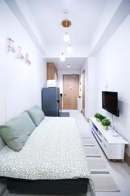a bedroom with a large bed and a refrigerator at Elegant yet Affordable condo in Pasay in Manila