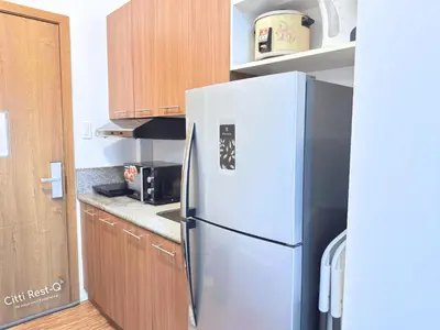 a white refrigerator in a kitchen with wooden cabinets at Studio City Alabang Pool Access Free for 2 Wifi & Netflix SC4 in Manila
