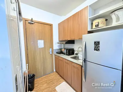 a small kitchen with a refrigerator and wooden cabinets at Studio City Alabang Pool Access Free for 2 Wifi & Netflix SC4 in Manila