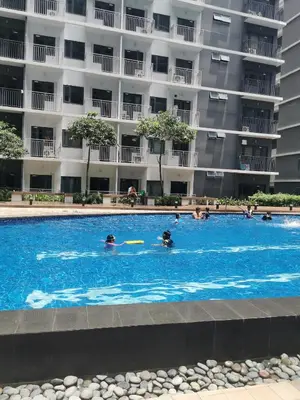people swimming in a swimming pool in front of a building at Mall of Asia Shore condo in Manila