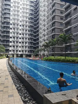 a man in a swimming pool next to tall buildings at Mall of Asia Shore condo in Manila
