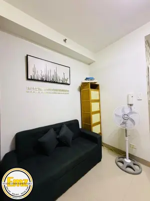 a living room with a black couch and a table at EMZ SHORE2 Staycation 16 in Manila