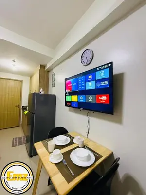 a dining room table with a clock on a wall at EMZ SHORE2 Staycation 16 in Manila