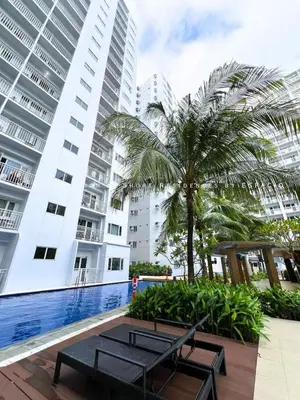 a resort with a pool and a palm tree and buildings at Ezpacio in Manila