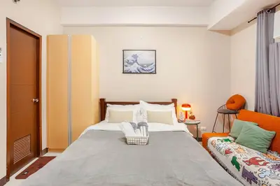 a bedroom with a bed and an orange chair at Roam & Rest Staycation near NAIA Manila Airport and free WiFi in Manila