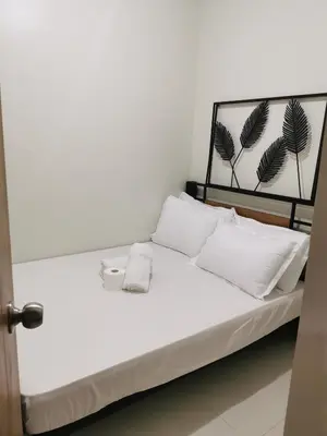 a white bed with white pillows and a black headboard at Mall of Asia shore 3 condotel in Manila