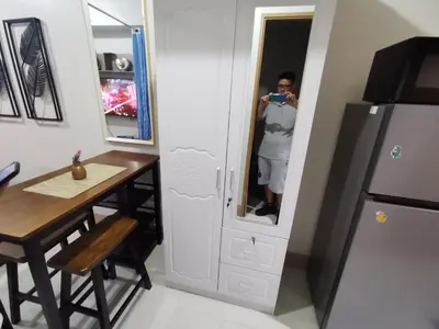 a woman taking a picture in a mirror in a kitchen at Mall of Asia shore 3 condotel in Manila