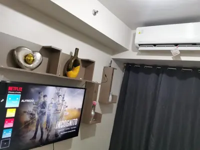 a living room with a tv and a curtain at Mao condotel shore 3 Pasay in Manila