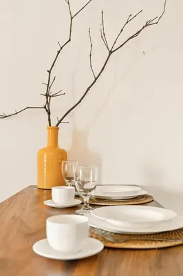 a wooden table with plates and glasses and a vase at Native studio hideaway in the heart of Poblacion, Makati in Manila