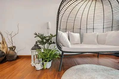 a rattan chair with pillows in a living room at Native studio hideaway in the heart of Poblacion, Makati in Manila