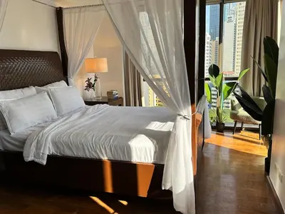 a bedroom with a bed and a view of a city at Tropical Wood Studio w Balcony Near Greenbelt Pool and Gym Access in Manila