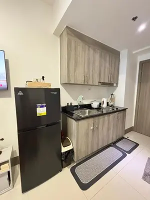 a kitchen with a black refrigerator and a sink at Fame Residences 1br unit by LaBelle in Manila