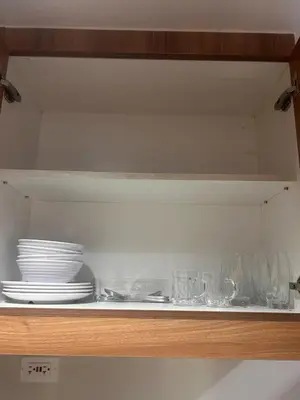 a shelf with plates and bowls and glasses on it at 1Bedroom Condo at Shore Near Airport & MOA Balcony Pool View in Manila