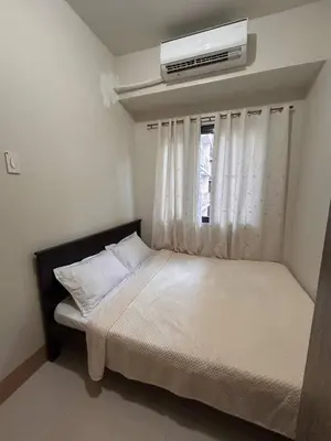 a small bedroom with a bed with a window at 1Bedroom Condo at Shore Near Airport & MOA Balcony Pool View in Manila