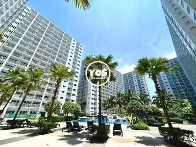 a clock in front of a large building with palm trees at Your Own Space Staycation in MOA in Manila