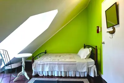 a bedroom with a green wall with a bed and a chair at Madie's Place B&B with Private Pool in Santa Rosa near Enchanted Kingdom in Santa Rosa