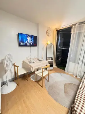 a living room with a table and a tv on the wall at Coziey Inn in Manila