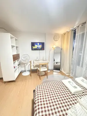 a bedroom with a bed and a table and a tv at Coziey Inn in Manila