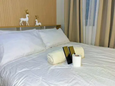 a bed with two towels and a book on it at Auberge Condotels B at SMDC Hope Residences in Trece Martires