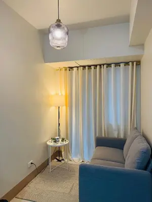 a living room with a blue couch and curtains at MOA Shore 3 One Bedroom Family Suite with Balcony in Manila