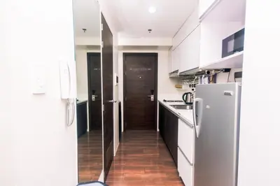 a kitchen with white cabinets and a hallway with a refrigerator at Netflix & Chill Stylish Makati condo gym swim park internet fast 2474 in Manila