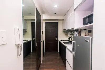 a small kitchen with white cabinets and a refrigerator at Netflix & Chill Stylish Makati condo gym swim park internet fast 2474 in Manila