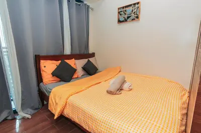 a bed with an orange comforter in a bedroom at Urban Luxe 1BR Makati central gym swim Park Fast Internet MB 3301 in Manila