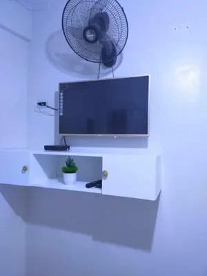 a television and a fan on a white wall at Eurica transient Inn Near Terminal 3 in Manila