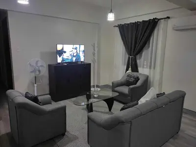a living room with two chairs and a table and a tv at LDN Pinecrest Two-room Suite in Manila