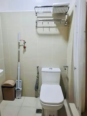 a bathroom with a toilet and a basket on the wall at City Escape in Manila