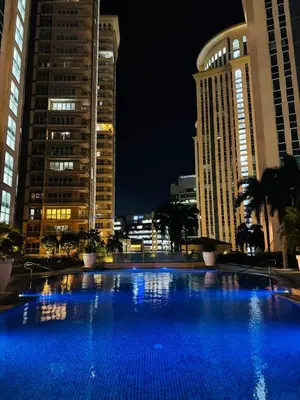a large blue swimming pool in a city at night at Condo Venice Luxury Residences Grand canal View in Manila
