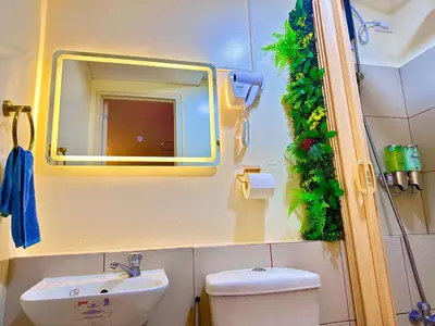 a bathroom with a sink and a mirror and a toilet at Cattleya Hearthstone in Manila