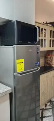 a refrigerator with a microwave on top of it in a kitchen at Fred Erick Staycation in Manila
