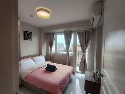 a bedroom with a bed with a suitcase on it at Facing Pool w Balcony MOA BP1741 in Manila