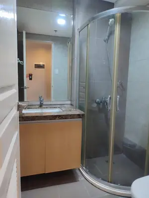 a bathroom with a shower and a sink at Facing Pool w Balcony MOA BP1741 in Manila