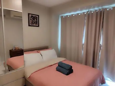 a small bedroom with a pink bed with a mirror at Facing Pool w Balcony MOA BP1741 in Manila