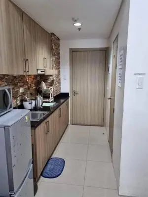 a kitchen with wooden cabinets and a door in a room at Staycation in Alabang Branch B in Manila