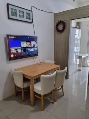 a dining room table with chairs and a television on the wall at Staycation in Alabang Branch B in Manila
