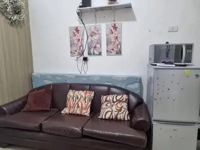 a brown leather couch with pillows in a living room at Staycation in Alabang Branch B in Manila