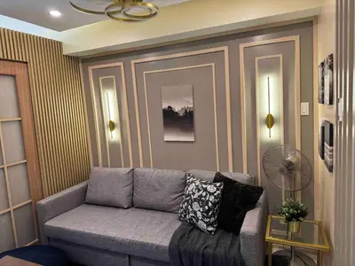 a living room with a gray couch and a fan at Shore 3 Residence Aesthetic 1 BR in Manila