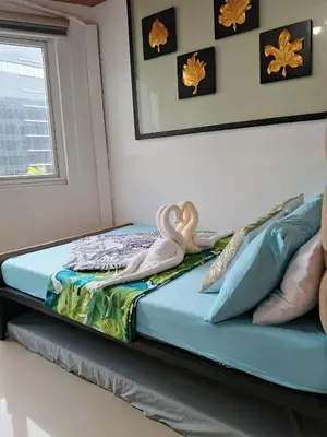 two swans sitting on a bed in a room at 503-1queen bed 1-pull out 1-sofa bed 1- extra matressedsa view in Manila